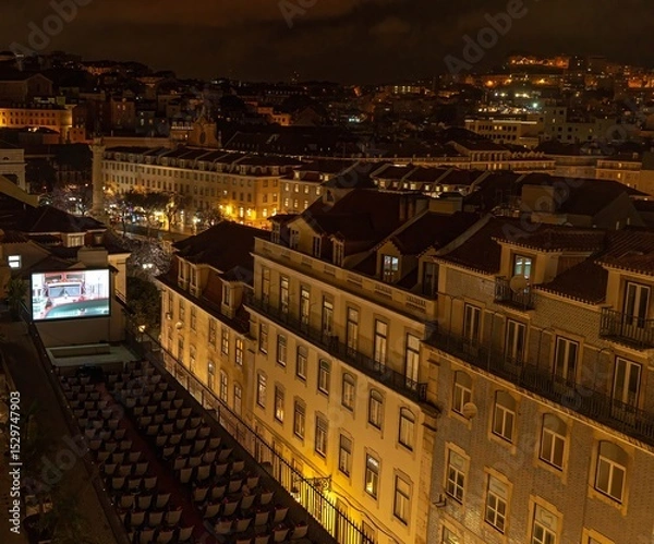 Obraz Viewers at a cinema on the roof of a tenement house in the Alfama district of Lisbon watch a film in the evening