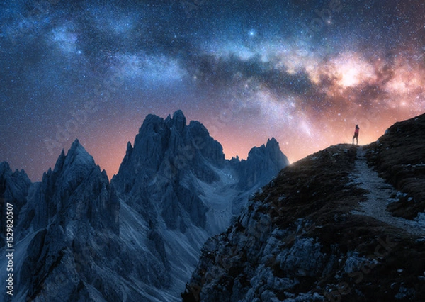 Obraz Glowing Milky Way and woman on mountain peak at starry night. Tre Cime, Dolomites, Italy. Galaxy. Space landscape with silhouette of a girl, trail, rocks, pink sky with stars. Milky Way and hiker