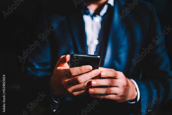 Fototapeta Business man with mobile phone in hands, close up view. Businessman in suit holding cell phone