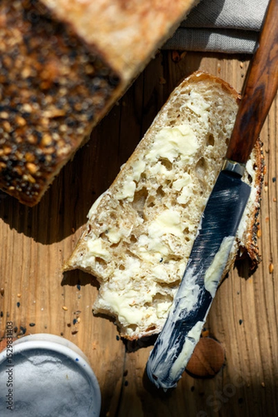 Obraz Top view of sliced white sourdough bread with butter and knife close up. Simple breakfast on wooden background