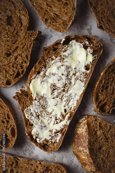 Obraz Top view of artisan sliced rye sourdough bread with butter close up. Simple breakfast on grey concrete table