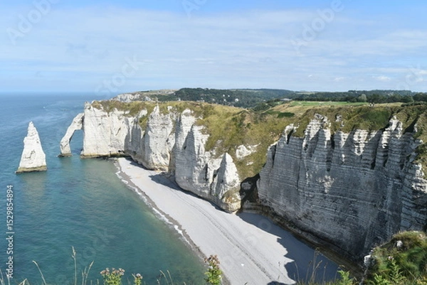 Obraz Plage et falaises d'Étretat, avec un rocher dans l'eau en forme de dent de requin.