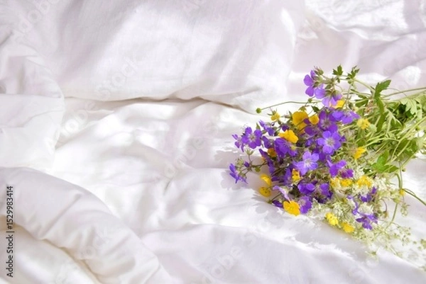 Obraz A bouquet of wild flowers in the bedroom on the bed in the morning.