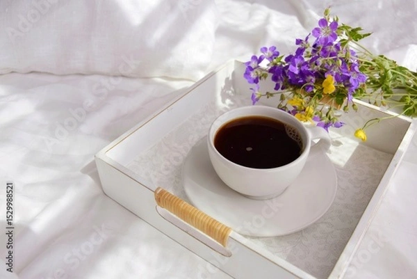 Obraz A bouquet of wild flowers and coffee on a tray in the bedroom on the bed in the morning.