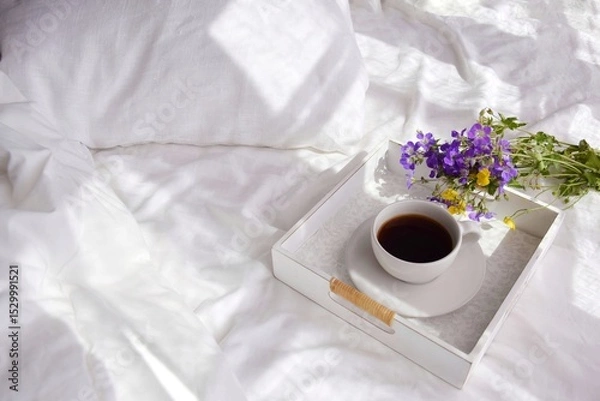 Obraz A bouquet of wild flowers and coffee on a tray in the bedroom on the bed in the morning.