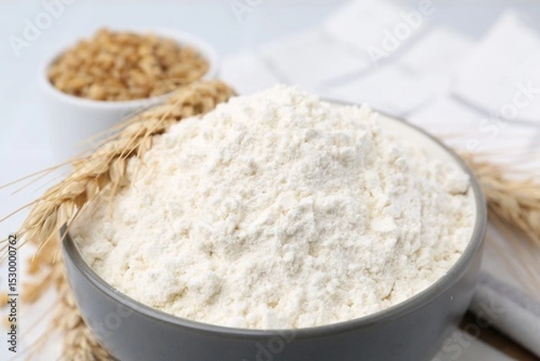 Fototapeta Wheat flour, grain and spikes on white table, closeup