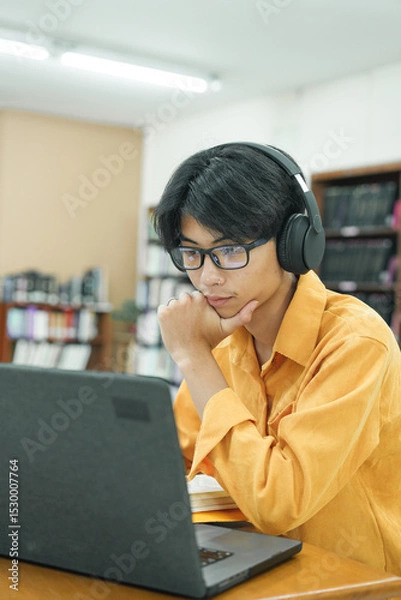 Obraz Young collage student using computer and mobile device studying online.