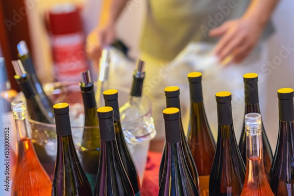 Fototapeta Assorted wine bottles with yellow caps arranged on ice bucket stand at public event. Concept of cold wine tasting, organized bar, social gathering, party