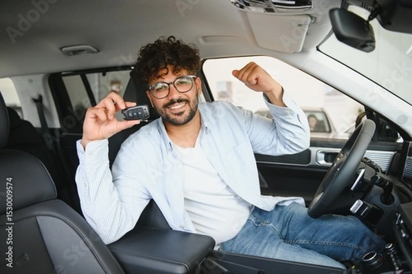 Fototapeta Happy man showing car key sitting in new vehicle at dealership