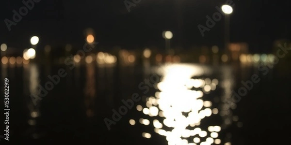 Fototapeta Blurred night scene featuring water reflections and distant lights creating bokeh effects in darkness