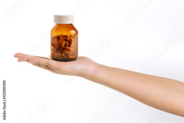 Obraz Hand holding a bottle of medicine isolated on white background.
