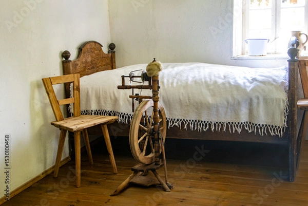 Obraz A spinning wheel beside the old bed