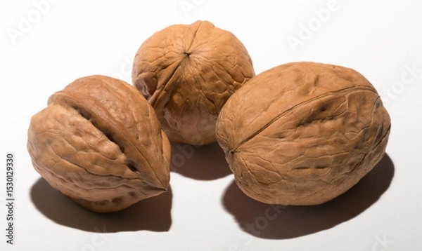 Fototapeta Three walnuts on a white background. The shell consists of three lobules.