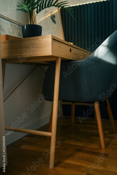 Obraz Modern wooden desk and dark upholstered chair in cozy home office corner with botanical wall art and indoor plant