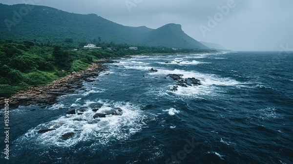 Fototapeta Rocky shoreline meets a vast ocean under a cloudy sky.