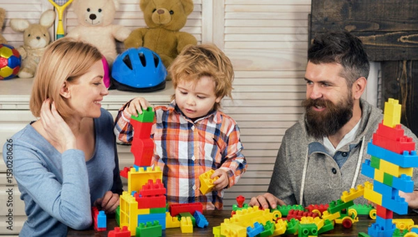 Fototapeta Family playing with colorful plastic building blocks at home. Happy family fun. Mother and father play with their son. Early childhood development, kids creativity. Family bonding. Family of 3.