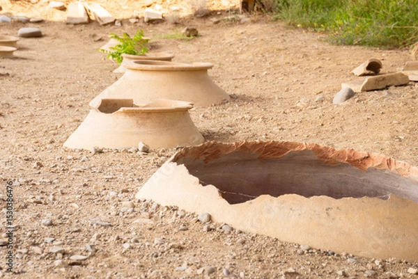 Fototapeta Clay wine vessels embedded in earth beneath wooden shelter at Armaziskhevi site, part of an ancient wine making cellar in Mtskheta region, Georgia