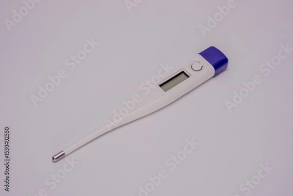 Fototapeta A sleek digital thermometer isolated on a white background. Designed for accurate body temperature measurement, it features a metallic tip and an LCD screen for clear readings.