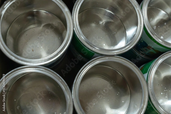 Obraz Rows of empty tin cans prepared for vibrant paint production. Empty vessels awaiting paint. Empty tin cans lined up in a paint factory. Rows of empty paint cans in an industrial setting.