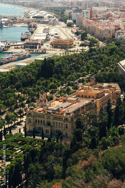 Fototapeta Historic architecture amidst lush greenery with a port city backdrop.