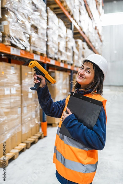 Fototapeta Warehouse worker scanning packages using barcode reader, managing inventory and logistics in a distribution center