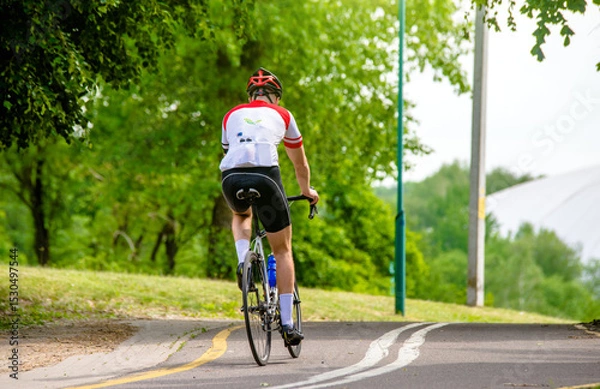 Fototapeta Cyclist ride on the bike path in the city Park
