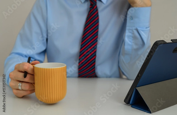 Obraz Businessman with a cup of coffee uses the internet