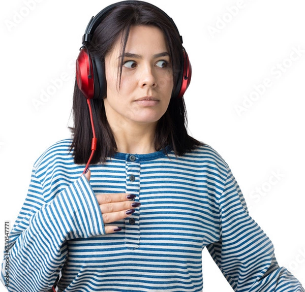 Fototapeta A young girl in a striped vest is listening to music in red headphones in a studio and dancing.