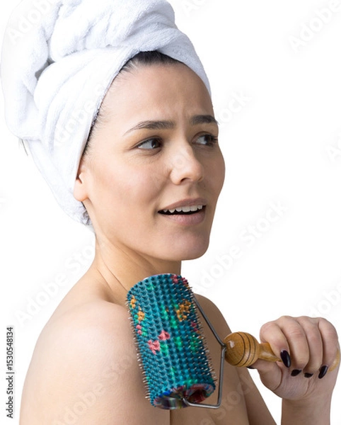 Fototapeta Brunette with a towel on her head using roller for face massage isolated on grey background
