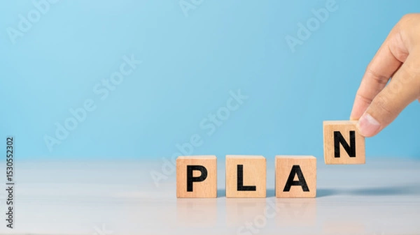 Obraz Close-up of hand holding a wooden block with the word PLAN. Symbol of strategy, vision, and organization in business.