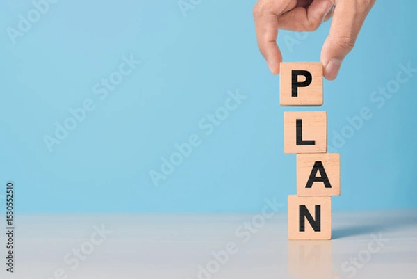Obraz hand shows wooden block with PLAN letters. Represents goal setting, business development, and management process.