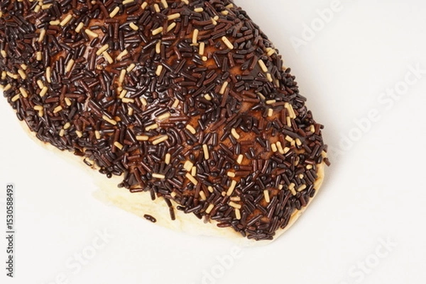 Fototapeta Milk bread with a soft white interior, topped generously with chocolate sprinkles and a touch of white topping. Photographed against a clean white background.