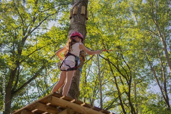 Obraz Rope climbing adventure in a lush forest with a young girl