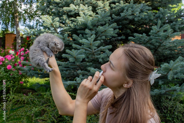 Fototapeta Woman Sneezing from Cat Allergy in Garden