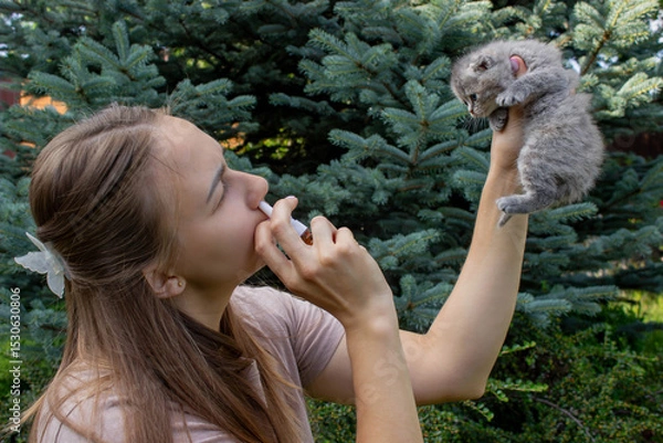 Fototapeta Woman Sneezing from Cat Allergy in Garden