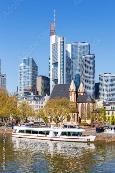 Fototapeta Frankfurt skyline skyscrapers with banks on River Main with excursion boat portrait format in Frankfurt, Germany