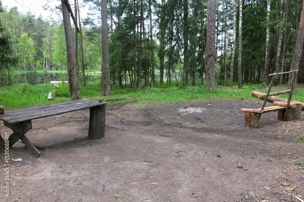 Fototapeta place of rest by a forest lake - a wooden table and a bench