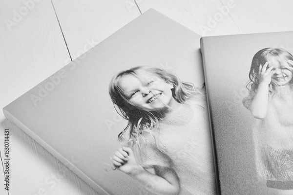 Fototapeta Two black and white canvas prints with child portraits, stretched on wooden stretcher bars with gallery wrapping. Displayed on a white wooden surface
