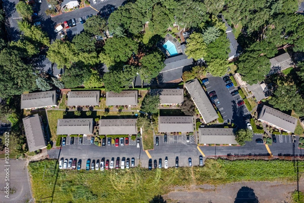 Obraz Aerial drone picture of a beautiful residential apartment complex in Cedar Mill, Portland, OR, captured at morning. Photo shows green courtyards, swimming pool, parking lots and housing buildings	
