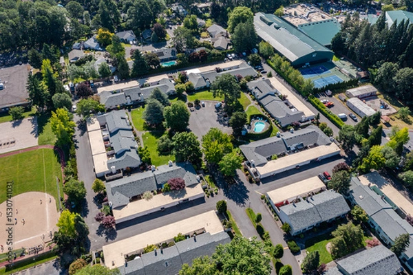 Obraz Aerial drone picture of a beautiful residential apartment complex in Cedar Mill, Portland, OR, captured at morning. Photo shows green courtyards, swimming pool, parking lots and housing buildings	
