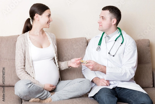 Fototapeta Doctor is giving pills to a pregnant woman and explaining how to use them. Treatment during pregnancy