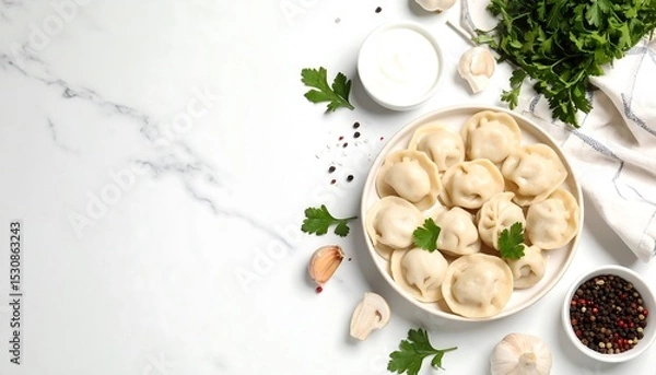 Fototapeta A top-down view of traditional pelmeni dumplings on a white marble table with sour cream, parsley, and garlic.