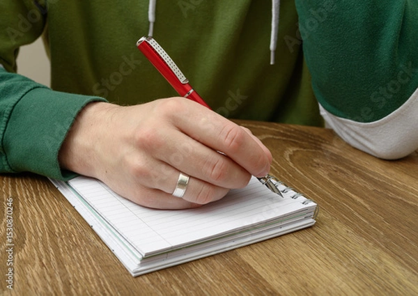 Obraz A depressed man sits at a table and writes a farewell letter.
