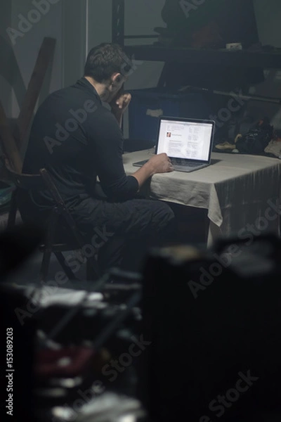 Obraz Man using laptop in dark room.