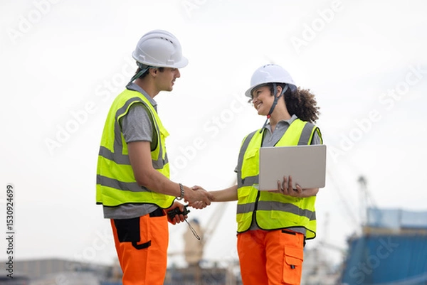 Fototapeta Young Industrial Workers Shaking Hands at a Port, Port Engineers Discussing Logistics at a Shipping Yard, Team of Maritime Professionals Planning at a Harbor