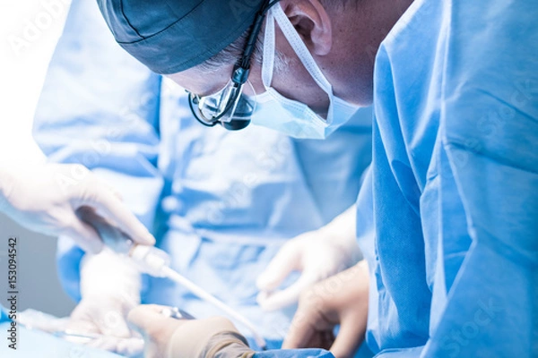 Fototapeta Męski dentysta w jednolitym operacji implantacji dentystycznej u pacjenta w biurze stomatologii.
