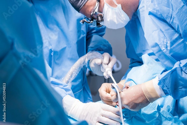 Fototapeta Lekarz dentysta w mundurze wykonuje operację implantacji zębów u pacjenta w gabinecie stomatologicznym.