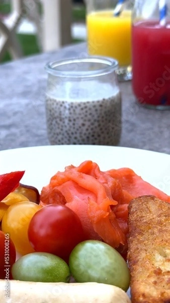 Fototapeta Cured meat lies beside cherry tomato, juicy grapes, sausages, bread cubes, juice and chia glass on sunlit table, offering rustic contrast at elegant tourist destination breakfast.