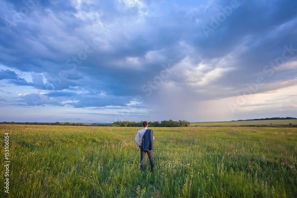 Fototapeta businessman in a suit walking on a spacious green field with a blue sky