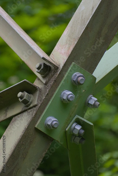 Fototapeta An imposing metal structure's bolted connections highlight industrial strength and precision against a stark sky, showcasing engineering detail
